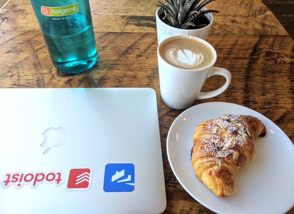 A plate of croissants with a latte beside a laptop.